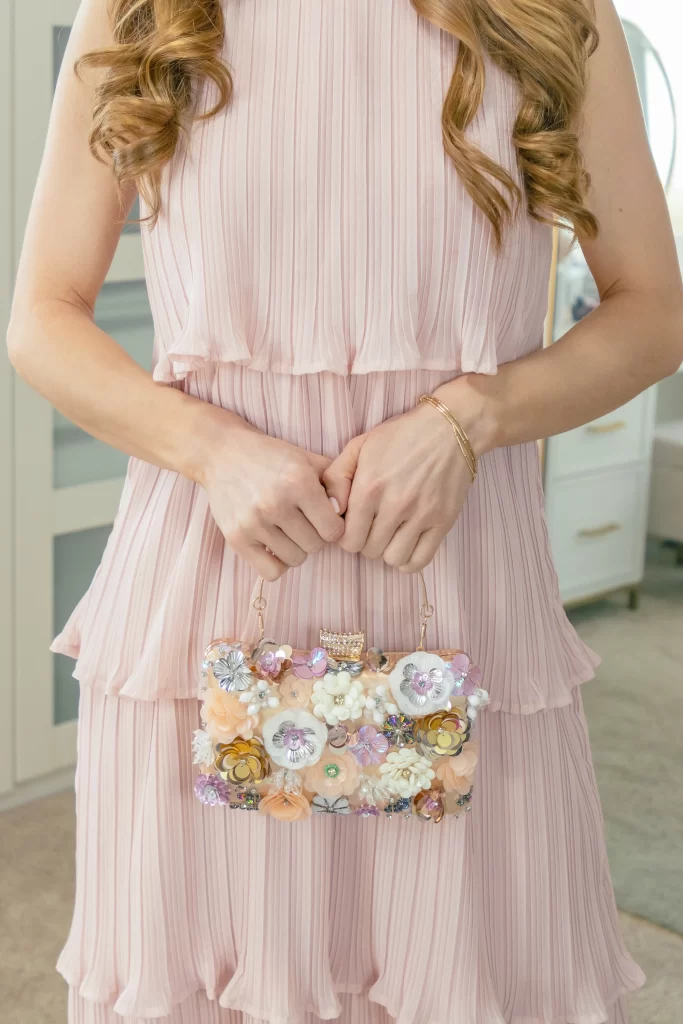 What to Wear to a Spring Wedding 2024: Floral clutch and pink tiered dress